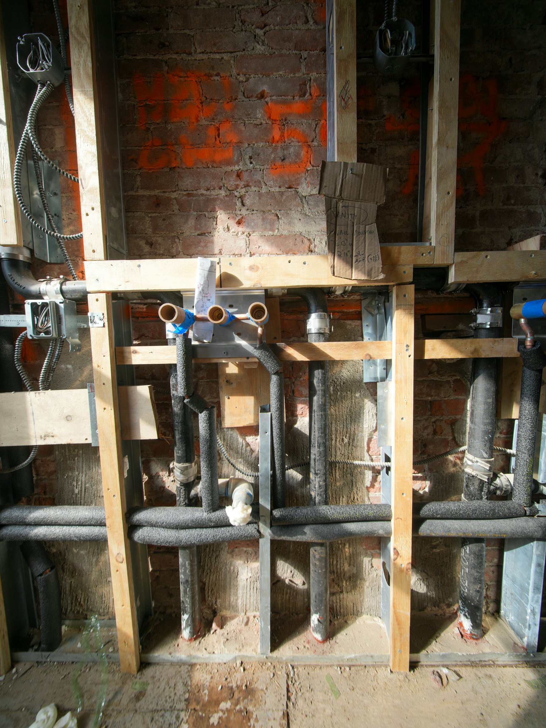 New plumbing being installed inside a wall frame