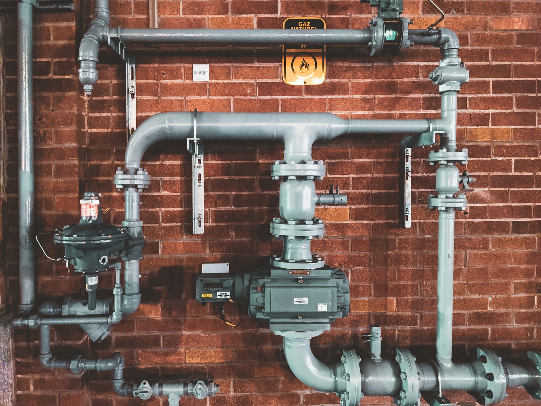 Steel pipes, valves and gauges on a brick wall